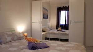 Une chambre à coucher avec un lit, une armoire et une table de chevet avec une lampe.