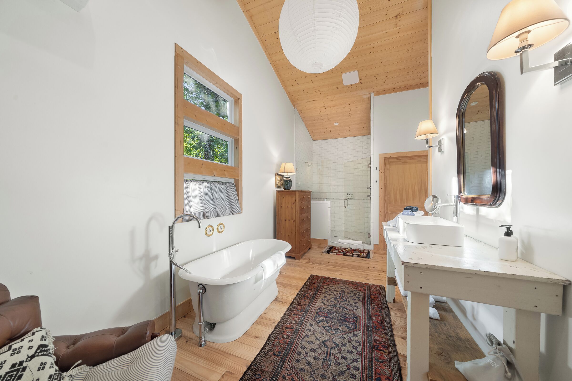 Ein Badezimmer mit einer freistehenden Badewanne, einem Holzkosmetikschrank mit Spiegel und einer Duschkabine.