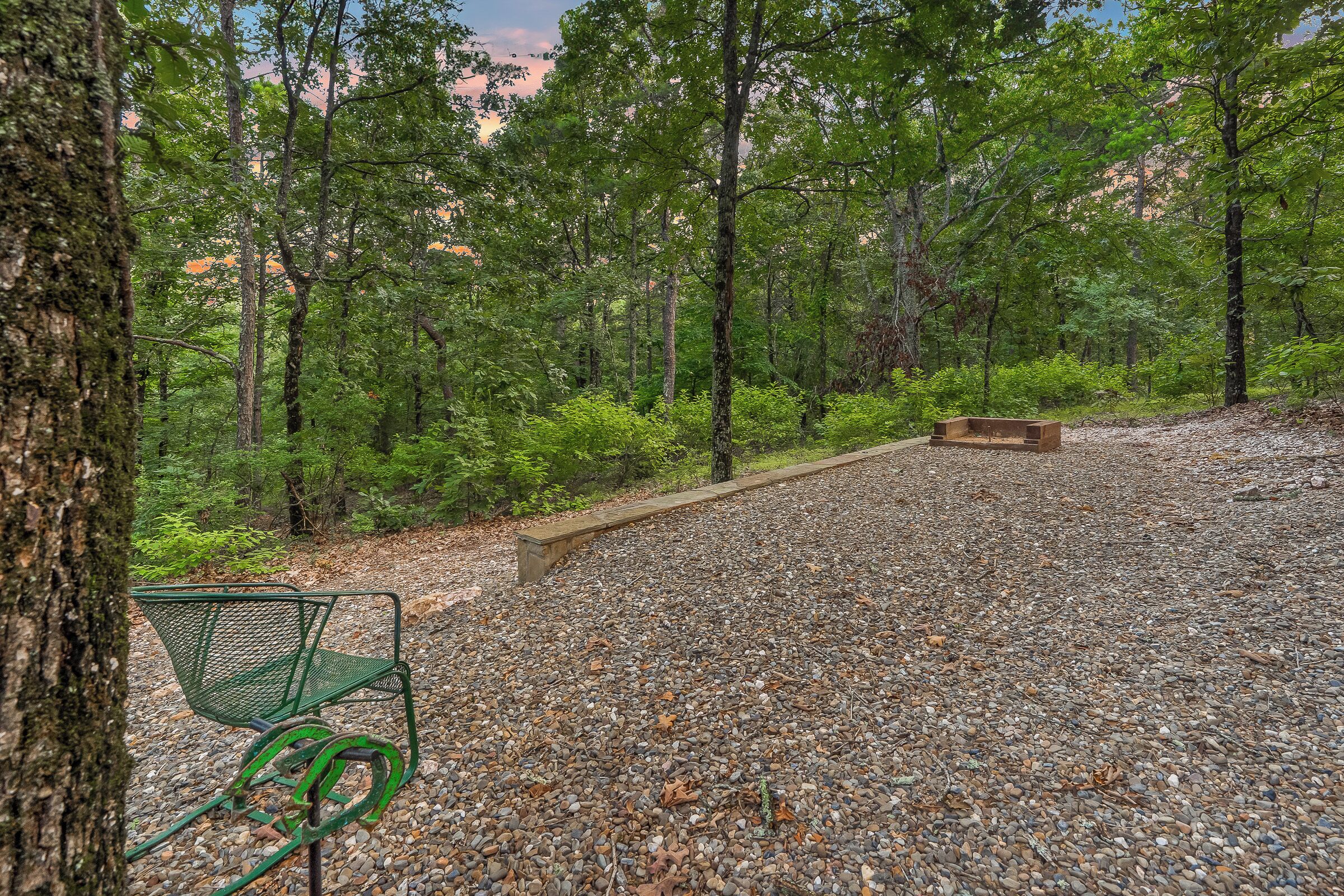 A park with a gravel path, a green metal bench, and a wooden bench.