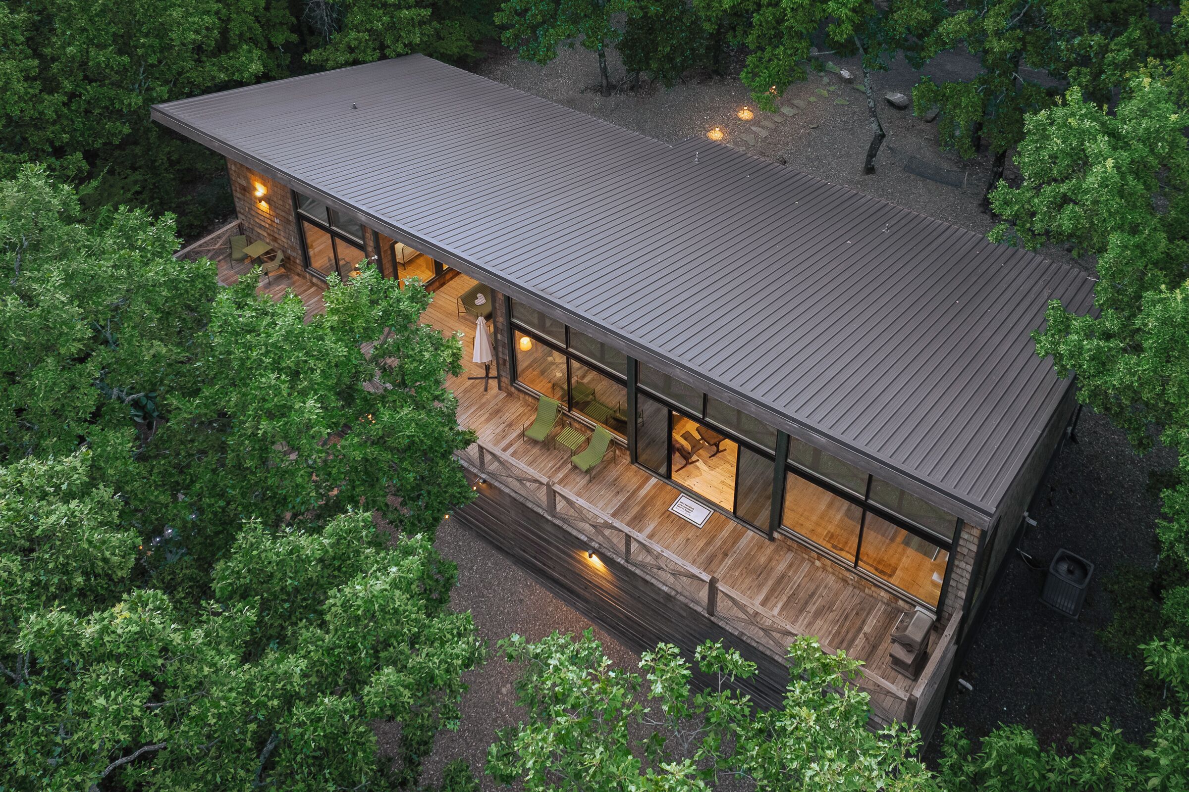 A modern house with a flat roof, large windows, and a wooden deck.