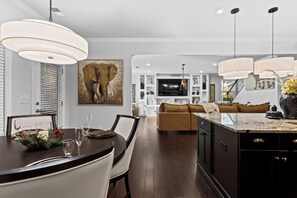 A modern kitchen with dark wood cabinetry, a marble countertop, and pendant lighting.
