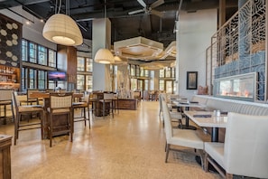 Un restaurante espacioso con techos altos, iluminación colgante y una combinación de asientos de madera y tapizados.