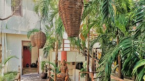 A serene indoor garden with a Buddha statue, wicker baskets, and lush greenery. - Rustik-inn (Playa del Carmen)