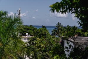 A coastal view with a communication tower, dense greenery, and a body of water. - Rustik-inn (Playa del Carmen)