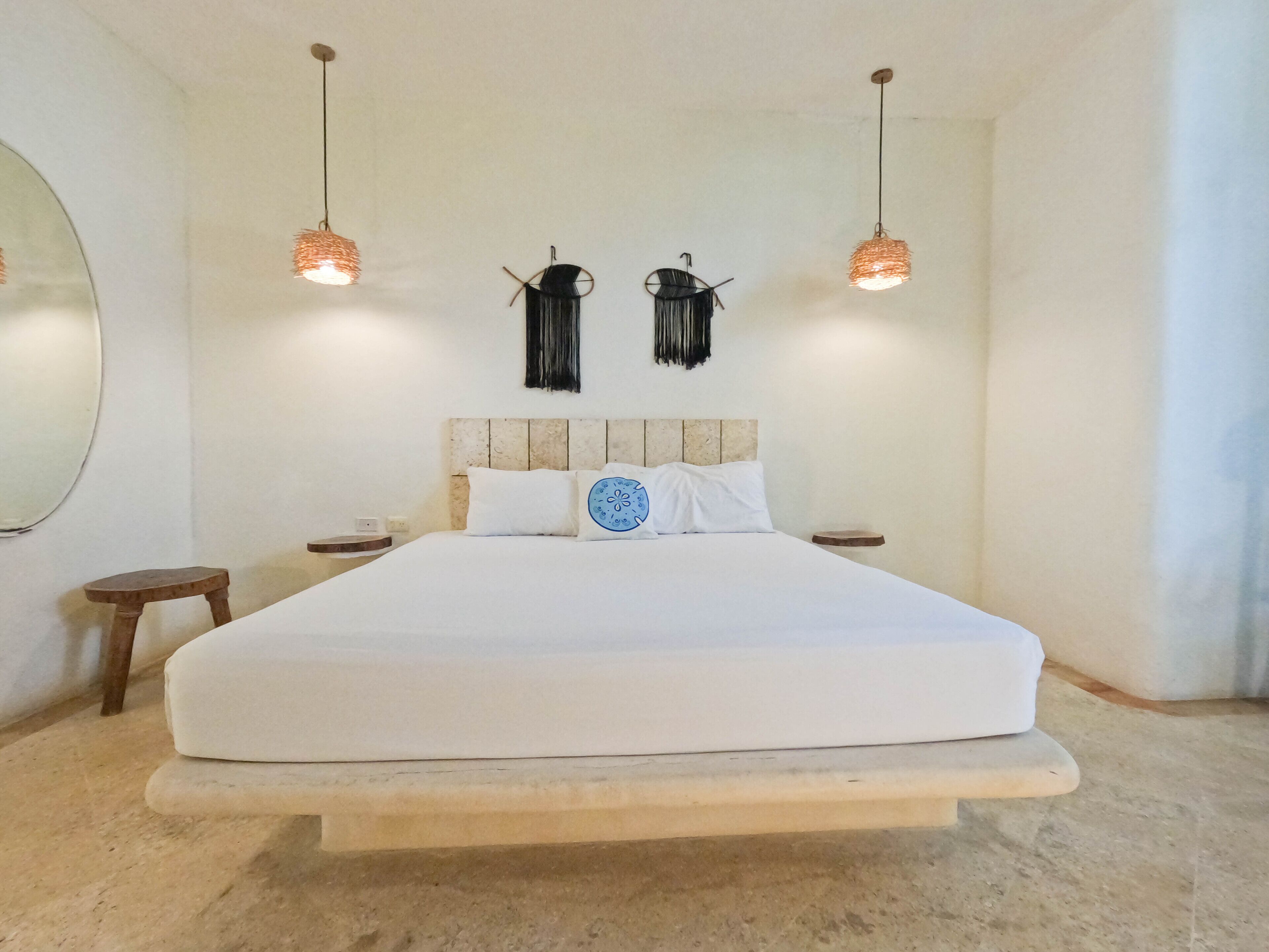 A large bed with a wooden headboard, two bedside tables, and hanging pendant lights.