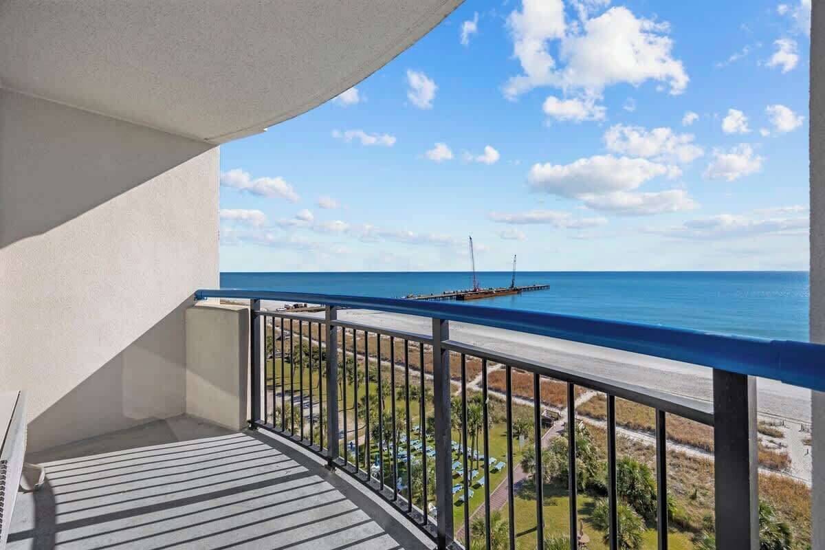 Un balcone con vista sull'oceano, una barca all'orizzonte e cielo sereno.