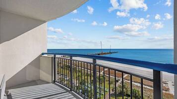 Un balcone con vista sull'oceano, una barca all'orizzonte e cielo sereno.