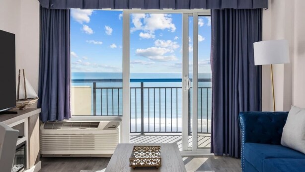 Una habitación con un amplio ventanal corredera que da a un balcón con vistas al mar.