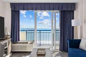 A room with a large sliding glass door leading to a balcony with a view of the sea. - The Renewed Sunrise Beach Suite (Myrtle Beach)
