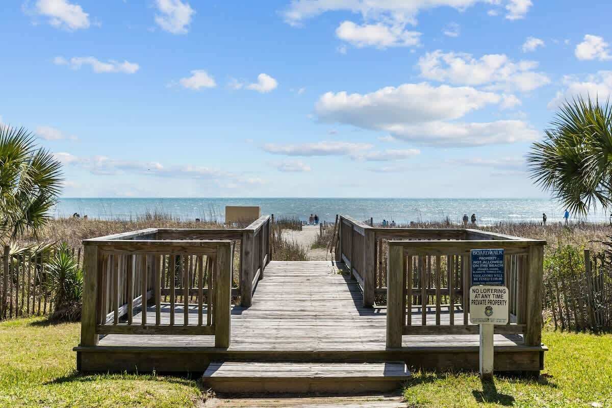 A wooden boardwalk leading to a beach with a sign indicating no loitering at any time.