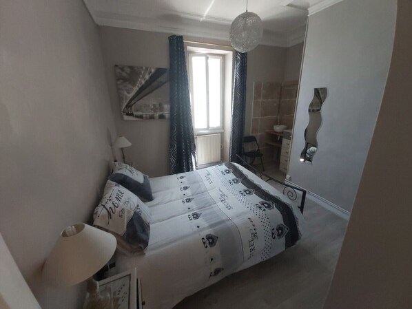 A bedroom with a bed, a bedside lamp, a window with curtains, a mirror, and a hanging light fixture. - House with a terrace offering a stunning panoramic view of La Ciotat Bay (La Ciotat)