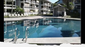 A hotel with a swimming pool, multiple balconies, and a small building with a sign. - Hilo SunShine Rental.2bds1ba,common swimming pool. (Hilo)