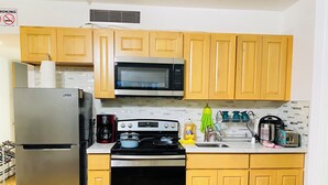 A kitchen with a stainless steel refrigerator, a microwave, a stove, and wooden cabinets. - Hilo SunShine Rental.2bds1ba,common swimming pool. (Hilo)
