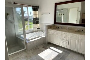 Enjoy a refreshing shower or soak in the standalone bathtub in this bathroom, complete with a large mirror above the vanity.
