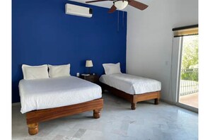 Two single beds with wooden frames and white bedding, a blue accent wall, and a ceiling fan.