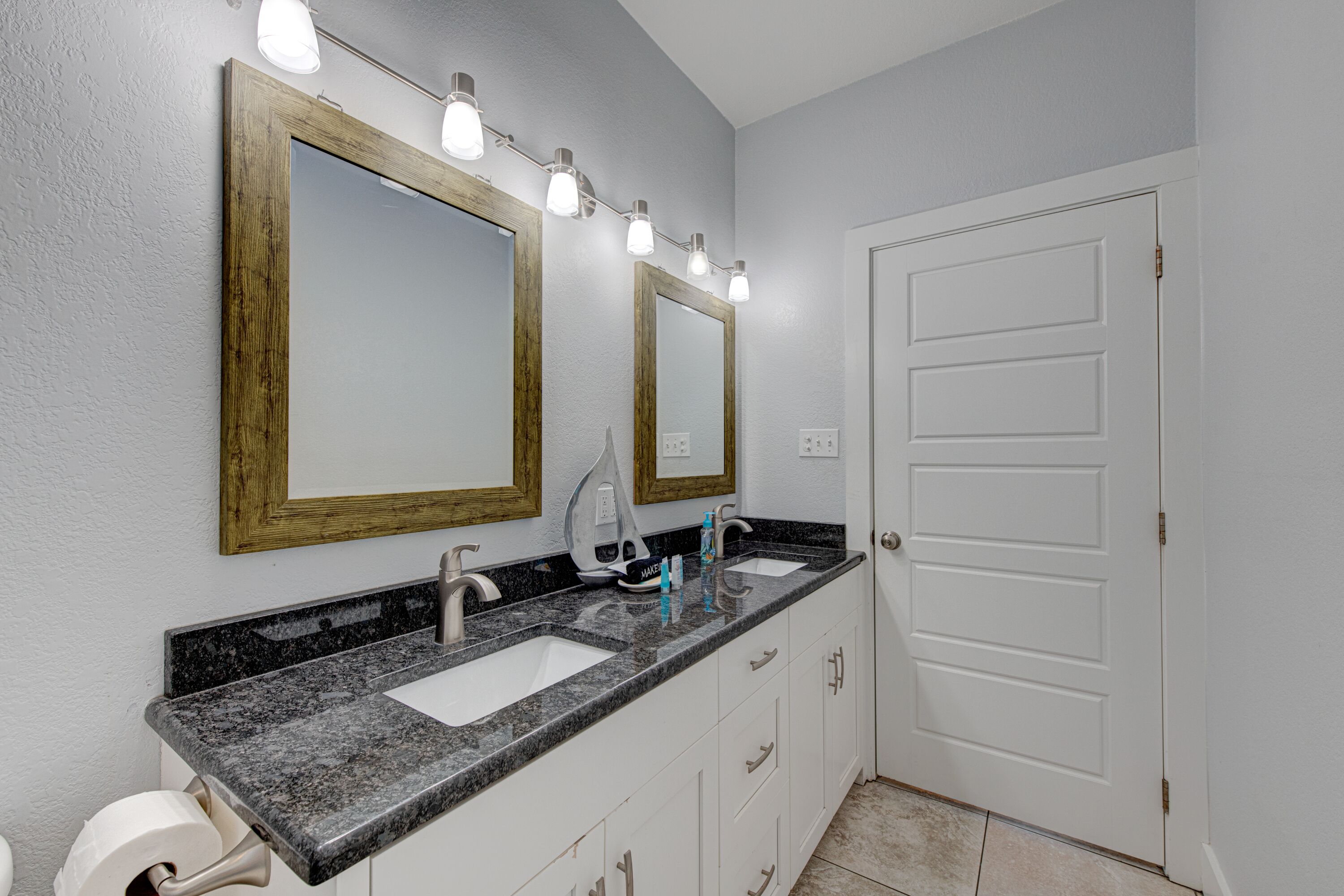 Une salle de bain avec deux lavabos, un miroir et une porte.