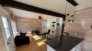 A modern kitchen with a central island, wooden flooring, and a ceiling fan. - The Glowbug Cottage (Morell)