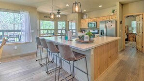 Una cocina amplia con una isla grande, taburetes de bar, armarios de madera y vistas al exterior.