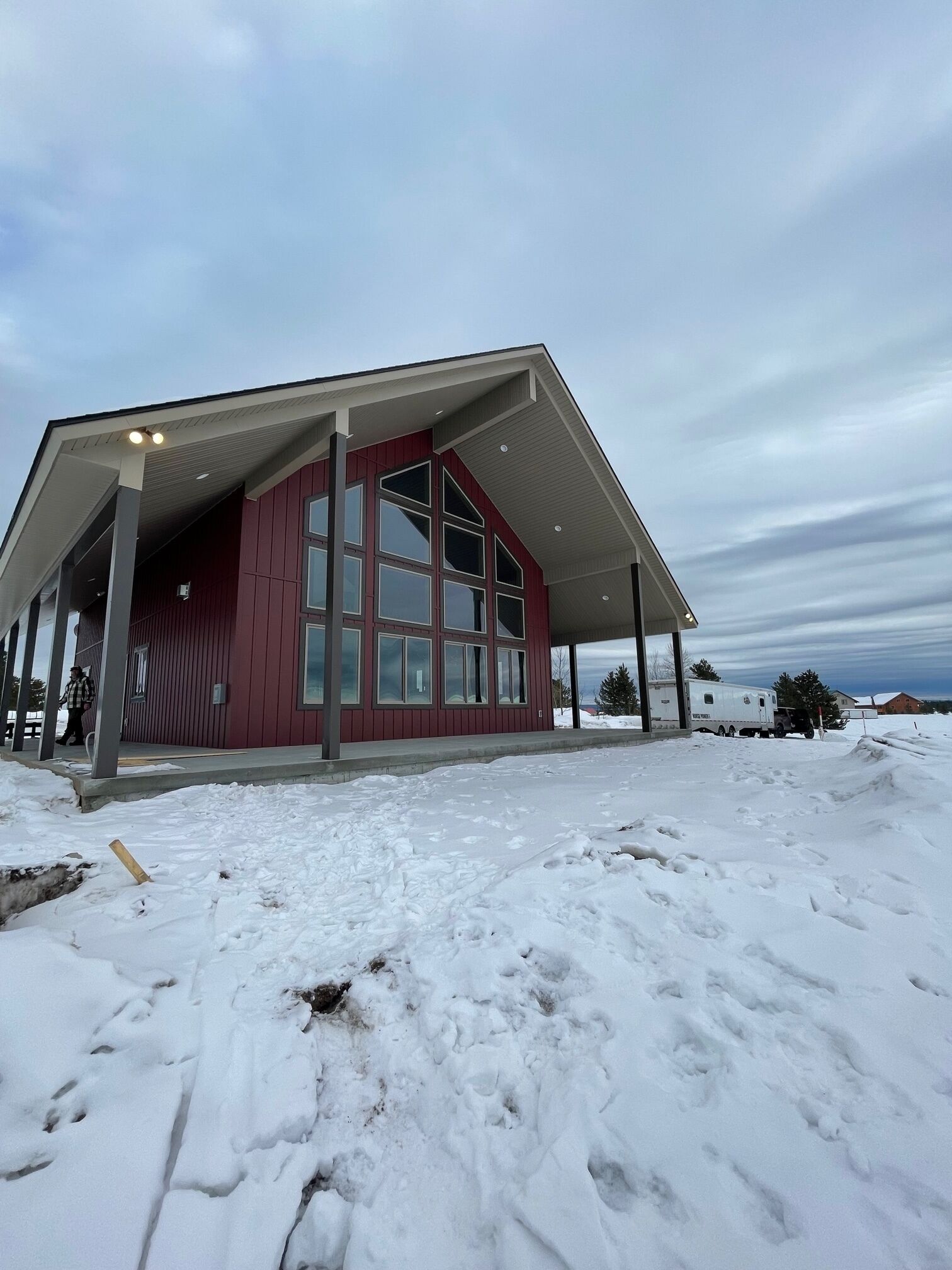 Un edificio moderno con fachada roja y ventanas amplias, rodeado de nieve.