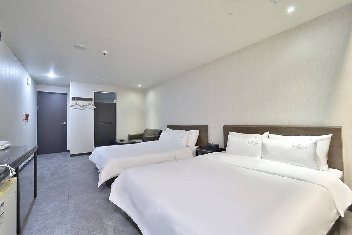 Una habitación de hotel con dos camas, un escritorio y un armario.