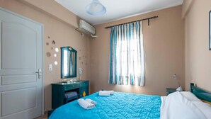 A bedroom with a bed, a dresser, a mirror, and a window with curtains. - Santorious Nice View Apartment (Santorini)