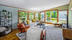 Ein geräumiges Wohnzimmer mit großem Fenster, einer Couch, einem Couchtisch und einem Ledersessel.