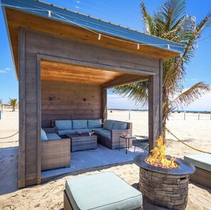 A covered outdoor seating area with a stone fire pit, wicker furniture, and a view of the beach. - Beautiful townhome in Wildwood Crest, walking distance to beach (Wildwood)