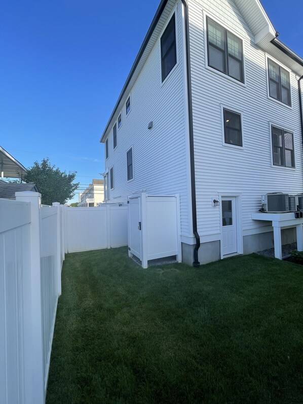 A two-story house with a white exterior, a fenced backyard, and a clear blue sky. - Beautiful townhome in Wildwood Crest, walking distance to beach (Wildwood)