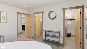 Un dormitorio con cama, mesita de noche, armario y una puerta que da a otra habitación.