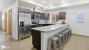 Una cocina moderna con una isla central, electrodomésticos de acero inoxidable y taburetes de bar.