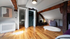 Une chambre spacieuse aménagée en mezzanine, avec des poutres apparentes, une grande fenêtre et une vue sur la ville.