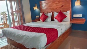 A bedroom with a wooden headboard, a red and white bedspread, and two bedside lamps. - Winter gardens mountain room (Munnar)