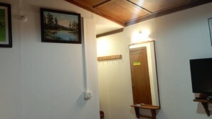 A room with a wooden ceiling, a framed painting of elephants, a framed landscape painting, a mirror, and a television. - Winter gardens mountain room (Munnar)