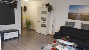 Un salon moderne avec un canapé noir, une table basse en verre et un tapis à motifs.
