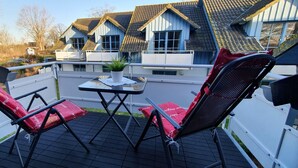 Un balcon avec deux fauteuils rouges dotés de coussins et une petite table sur laquelle est posée une plante.