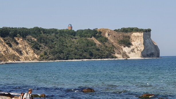 Un paysage côtier caractérisé par une falaise imposante et un bâtiment surmonté d’un dôme.