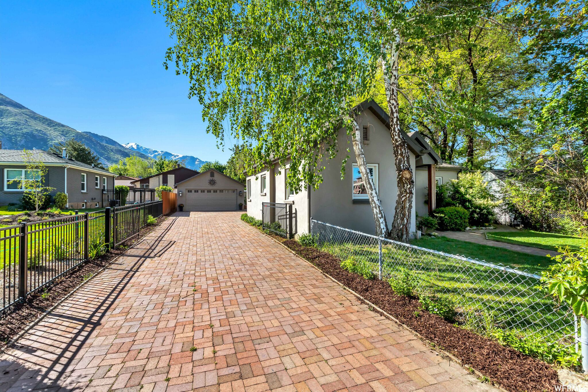 Un chemin pavé mène à une rangée de maisons, avec une chaîne de montagnes en arrière-plan.