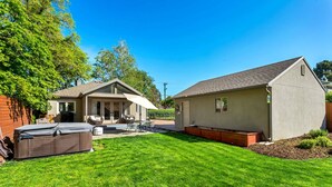 Un jardin avec une terrasse, un jacuzzi et un abri de jardin.