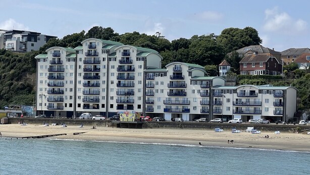 Un hôtel à plusieurs étages doté de balcons, situé près d’une plage.