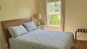 A neatly made bed with a floral-patterned bedspread, a wooden headboard, and two pillows.