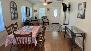 A dining area with a wooden table and chairs, a ceiling fan, and a door with a frosted glass window.