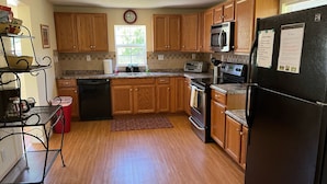 A kitchen with wooden cabinets, a black refrigerator, a microwave, a toaster, and a dishwasher.