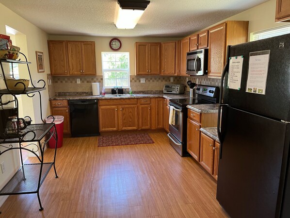 A kitchen with wooden cabinets, a black refrigerator, a microwave, a toaster, and a dishwasher.