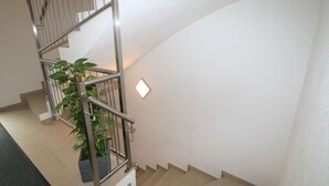 Eine moderne Treppe mit Metallgeländer, einem Blumentopf und einer Wandleuchte.