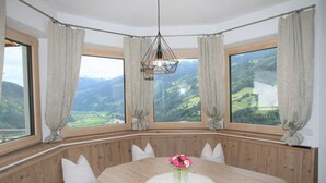 Eine Essecke mit Holztisch, weißen Kissen und einem Blumenstrauß.