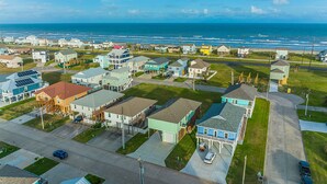 Zona residencial costera con casas, una carretera y una playa al fondo.