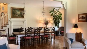 Un comedor con una mesa y sillas de madera, una araña y una planta grande.