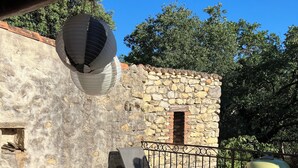 Une terrasse avec des sièges d’extérieur, un mur en pierre et un barbecue.