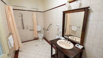 A bathroom with a shower, toilet, sink, and mirror.