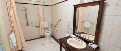 A bathroom with a shower, toilet, sink, and mirror.